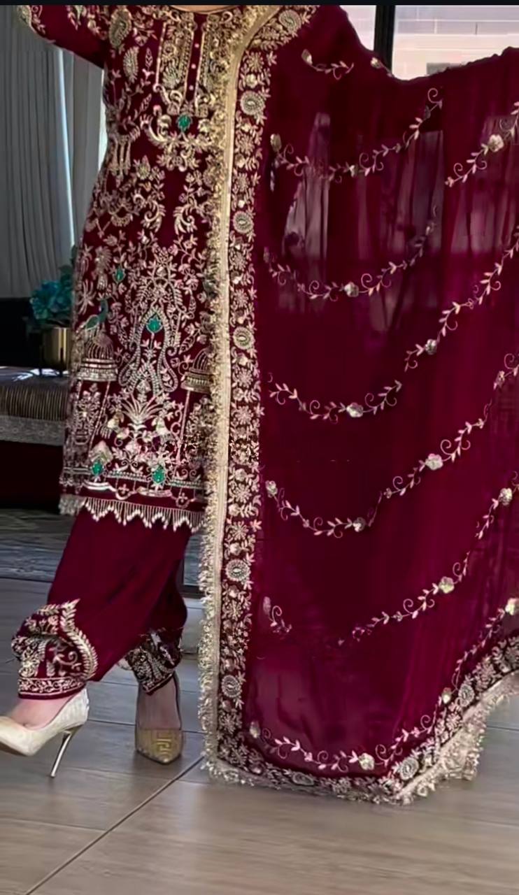 Maroon embroidered traditional outfit with gold detailing on a wooden floor.
