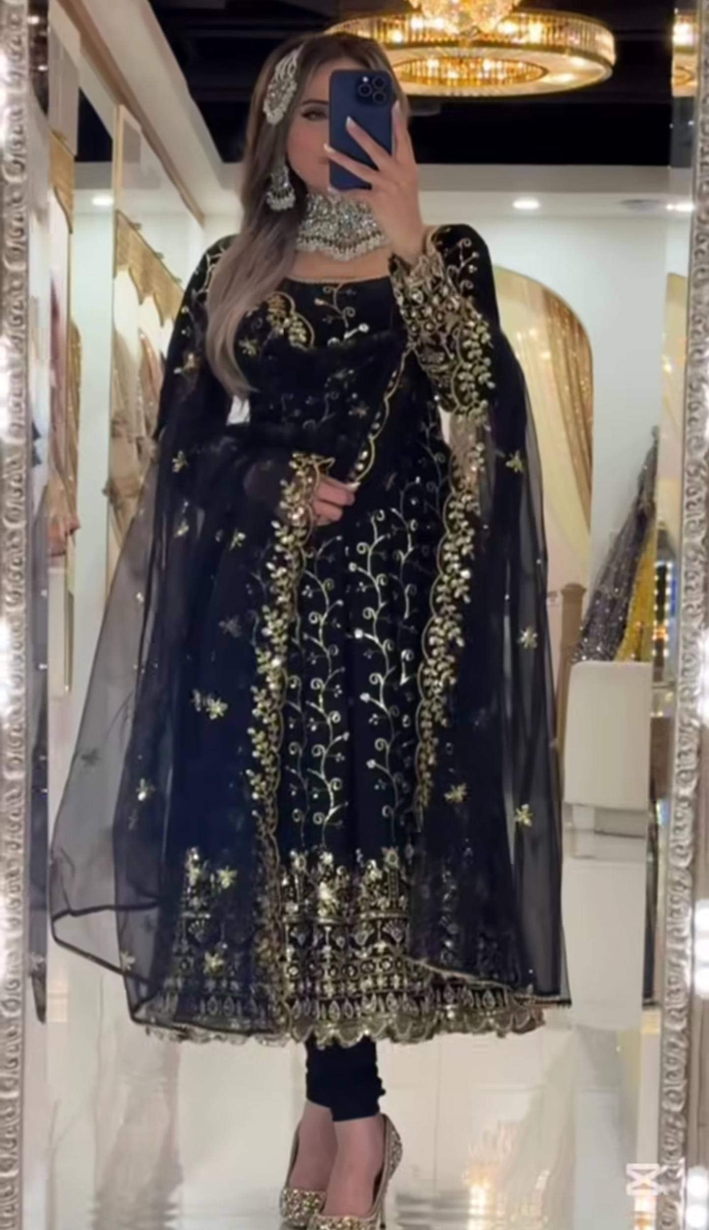 Person wearing a black and gold embroidered traditional outfit in a mirror selfie.