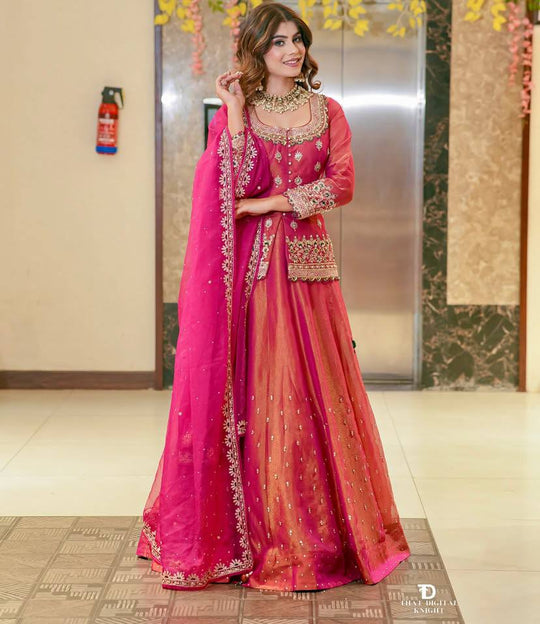 Pink and orange embroidered crop top lehenga with matching dupatta worn by a woman, designer ethnic party wear outfit